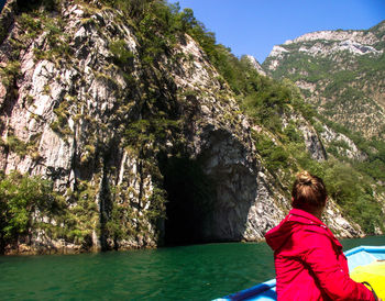 Woman on boat in river against rocky mountains