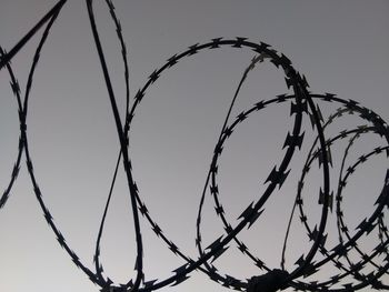 Low angle view of razor wire against clear sky