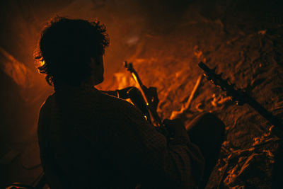 Rear view of man sitting outdoor at night