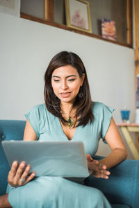 Portrait of young woman sitting on sofa at home