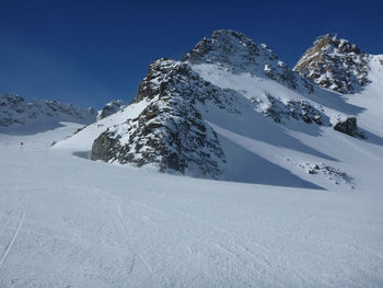 Scenic view of snow covered mountains against blue sky