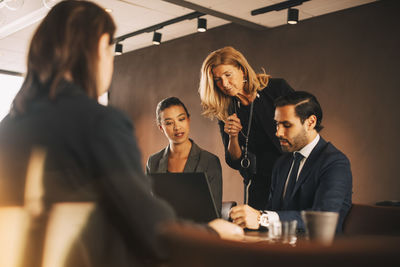 Mature female professional discussing with lawyers at office