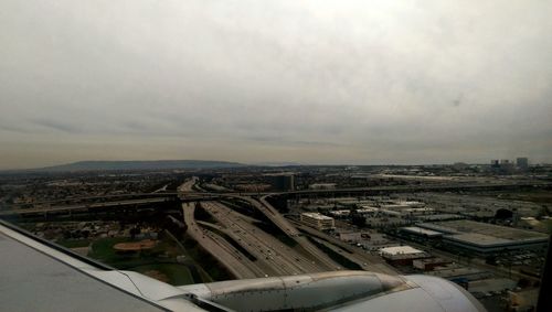 Aerial view of cityscape against cloudy sky