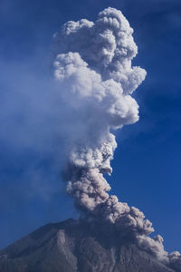 Low angle view of smoke emitting from volcanic mountain against sky