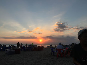 People on beach against sky during sunset