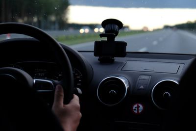 Cropped hand driving on road during sunset