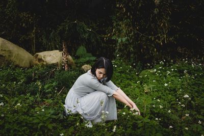 Woman sitting on field in forest