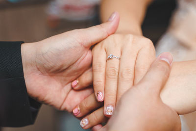 Groom and bride holding hands with rings