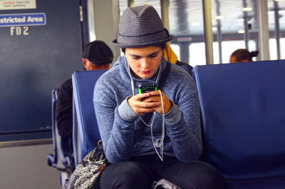 Young man using mobile phone while sitting in bus