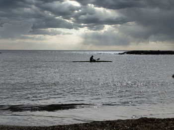 Silhouette people on sea against sky