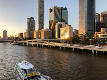 Modern buildings by river against sky in city