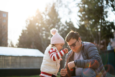 Daughter playing with father against trees