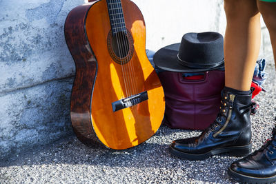Low section of person standing by guitar and hat on footpath