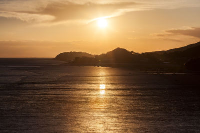 Scenic view of sea and silhouette mountains against sky during sunset