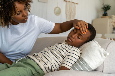 Loving worried african american woman mother taking care of sick child son at home