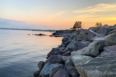 Rocks on shore against sky during sunset