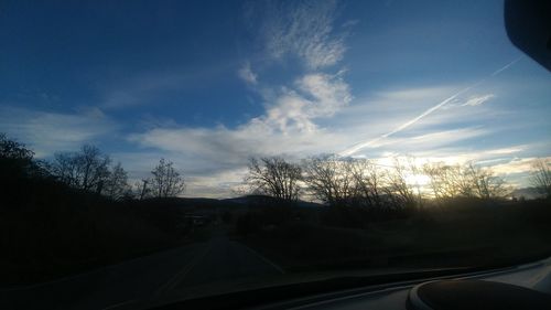 Road amidst trees against sky seen through car windshield