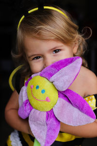 Smiling eyes. little girl hiding her smile , behind big purple flower toy.