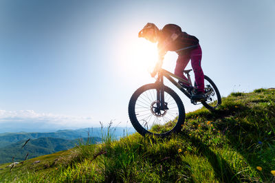 Cyclist man riding mountain bike outdoors. male tourist riding bicycle on grassy path in mountains