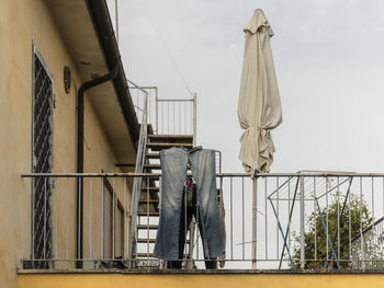 Low angle view of man standing by railing against sky