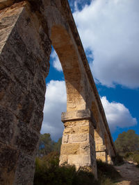 Low angle view of old ruin building against cloudy sky