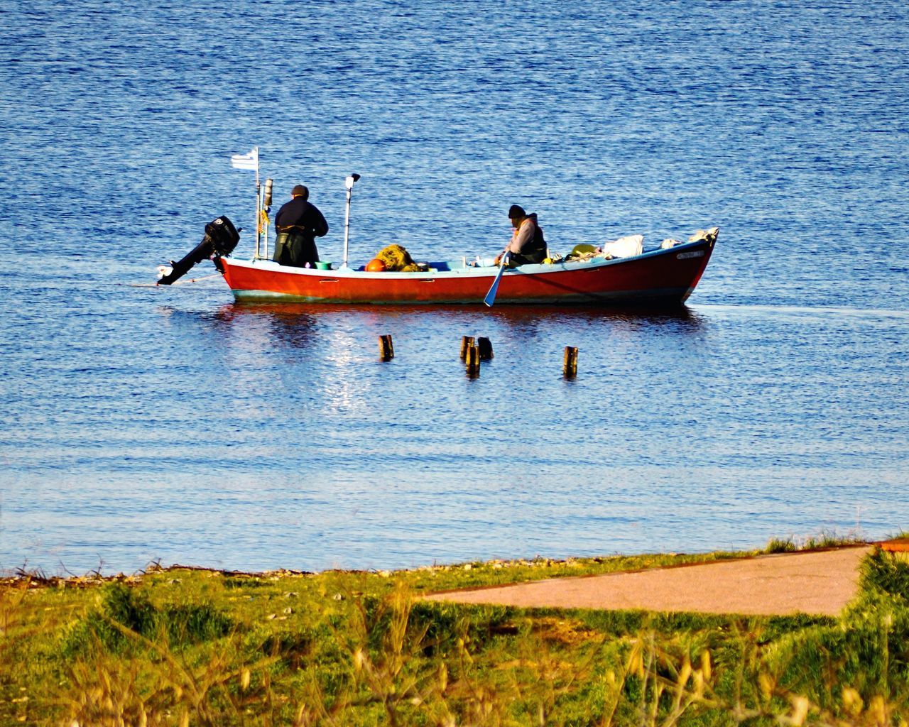 MEN SITTING ON BOAT IN SEA