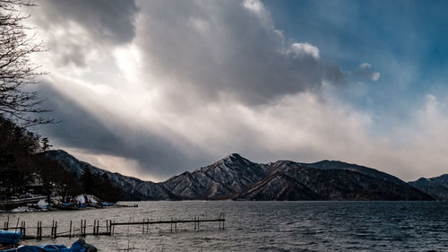 Scenic view of lake by snowcapped mountains against sky