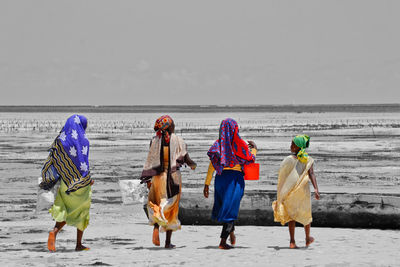 Rear view of people walking on beach