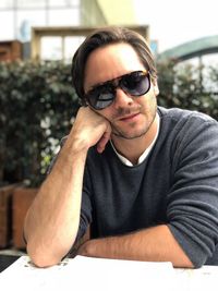 Portrait of young man wearing sunglasses sitting on table