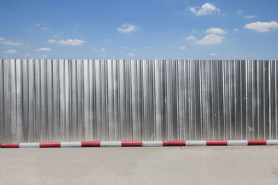 Corrugated iron by road against sky