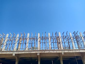 Low angle view of construction site against clear blue sky