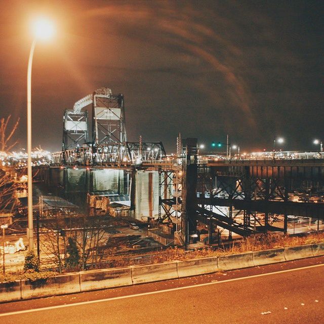 illuminated, night, architecture, built structure, building exterior, street light, lighting equipment, sky, street, city, transportation, road, outdoors, light - natural phenomenon, railing, electric light, the way forward, no people, building, electricity