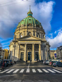 View of city street against cloudy sky