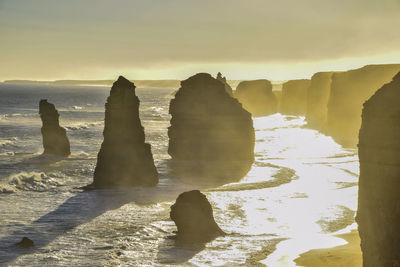 Rocks on beach against sky during sunset