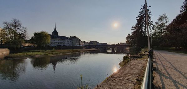 Buildings by river against sky in city