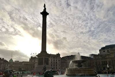 Statue in city against cloudy sky