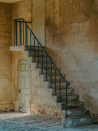 Staircase with black iron rail in yard with old doors