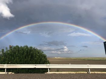 Scenic view of rainbow over field against sky