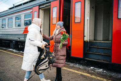 Girl escorts a friend to the train, helps carry a bag