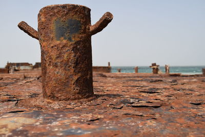 Close-up of rusty metal on beach against sky