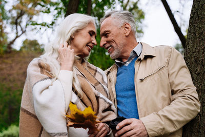 Smiling couple embracing while standing at park