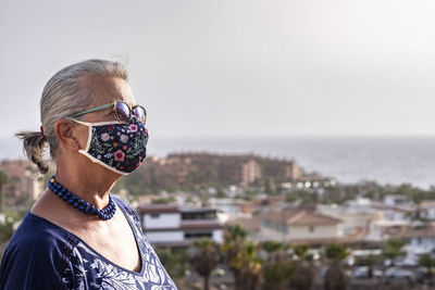 Close-up of senior woman standing against townscape