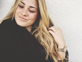 Close-up of smiling young woman against wall