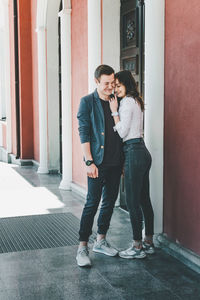 Full length of friends standing against wall