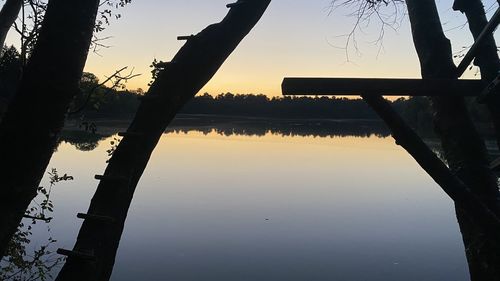 Silhouette trees by lake against sky during sunset