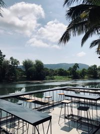 Chairs and table by swimming pool against sky