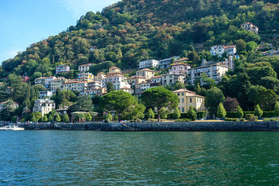 Buildings by river against mountain