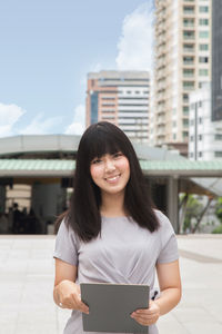 Young businesswoman standing against buildings in city