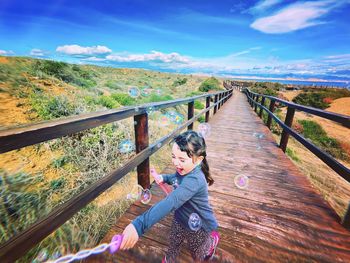 Rear view of woman walking on footbridge