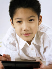 Portrait of boy holding digital tablet against white background